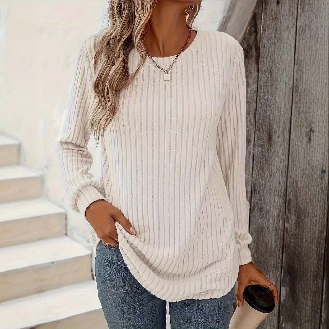 Frau in weißem gestreiftem Langarmshirt und blauer Jeans hält Kaffeebecher. Lässige Mode, Herbstoutfit, Damenbekleidung.
