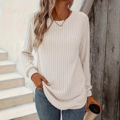 Frau in weißem gestreiftem Langarmshirt und blauer Jeans hält Kaffeebecher. Lässige Mode, Herbstoutfit, Damenbekleidung.