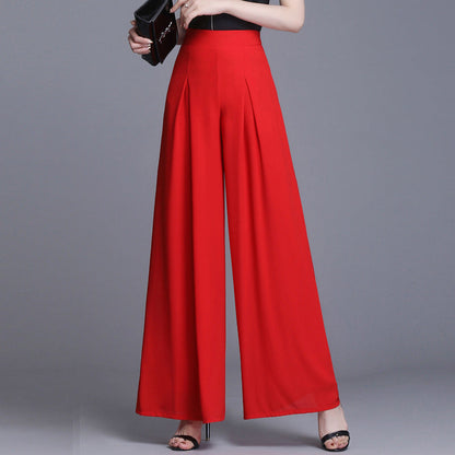Frau in eleganter roter Palazzo-Hose, schwarze High Heels, grauer Hintergrund. Modetrend, Damenbekleidung, stilvolle Hosenmode.