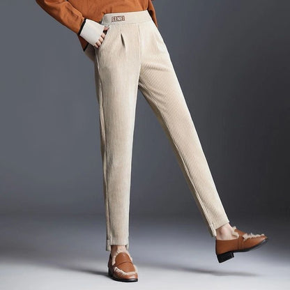 Beige Cordhose für Damen, kombiniert mit braunen Loafers und einem orangefarbenen Pullover. Modetrend Herbst, stilvolle Damenbekleidung.