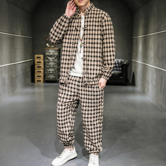 Mann in kariertem Anzug, lässiger Stil, moderne Mode, grauer Raum, weiße Sneakers, trendige Herrenbekleidung, urbaner Look.