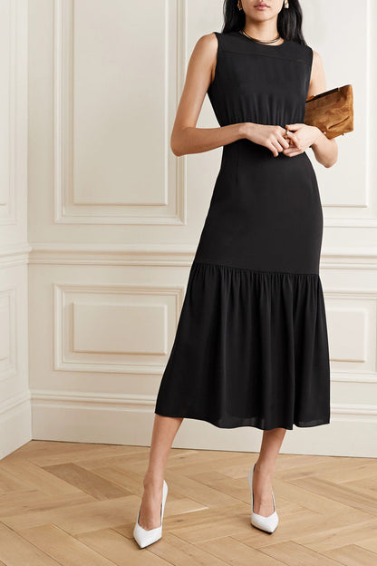 Frau in elegantem schwarzen Midikleid mit Rüschen, hält braune Clutch, trägt weiße Pumps. Stilvolle Abendmode, klassisch und zeitlos.