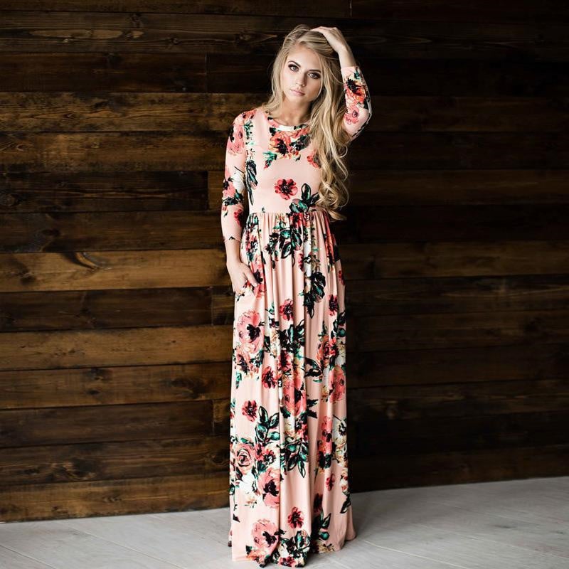Eine Frau in einem langärmeligen, blumigen Maxikleid vor einer Holzwand. Elegantes, florales Design, Mode, Damenbekleidung.