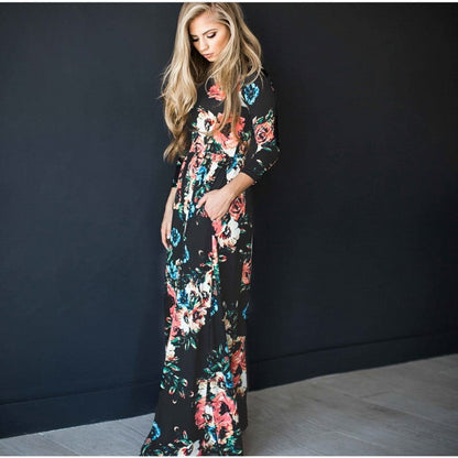Frau in langem, geblümtem Kleid vor schwarzem Hintergrund. Elegantes Maxikleid, florales Muster, Modefotografie, stilvolle Damenbekleidung.