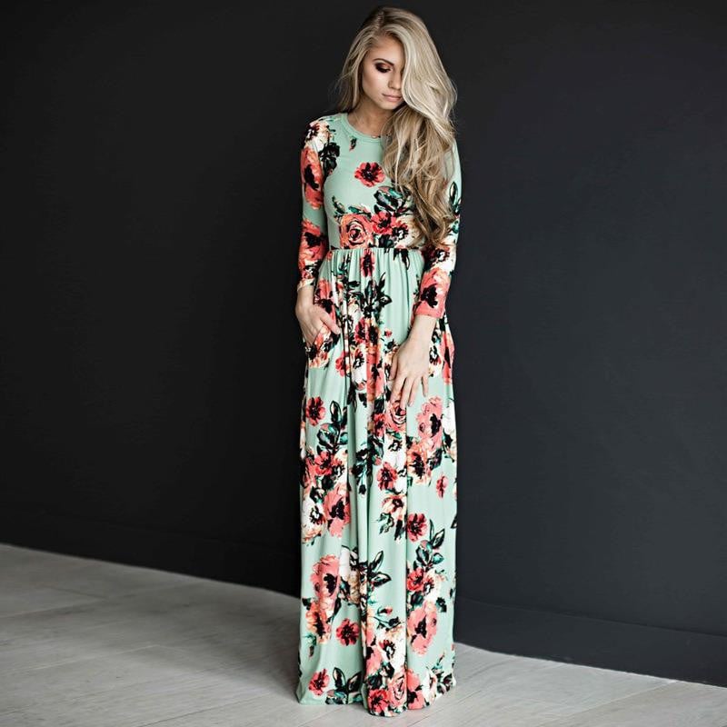 Frau in langem, geblümtem Kleid vor schwarzem Hintergrund, modisches Maxikleid mit Blumenmuster, elegantes Damenoutfit, stilvolle Abendmode.