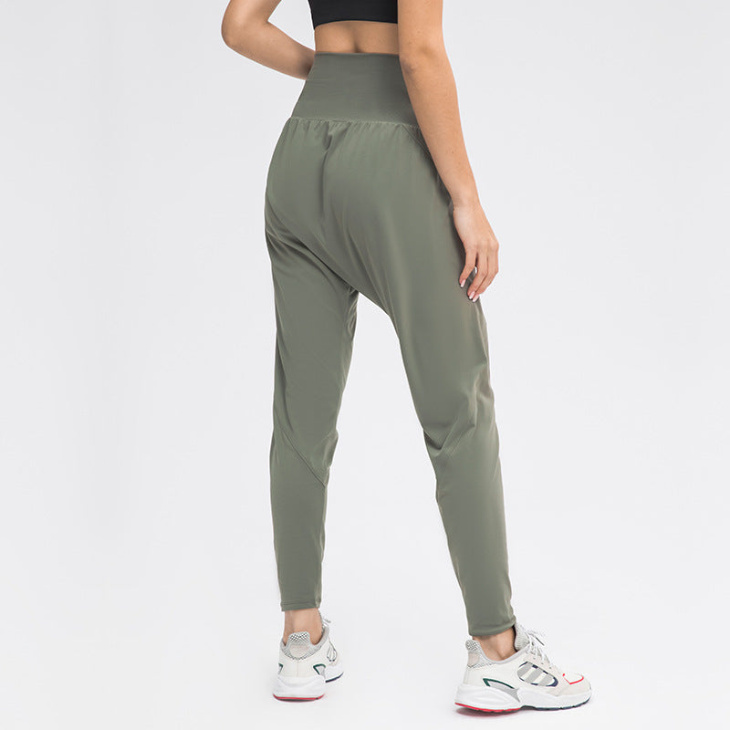 Frau in olivgrüner Jogginghose und weißen Sneakers, Rückansicht. Sportbekleidung, Fitnessmode, bequeme Damenhose, athletischer Stil.