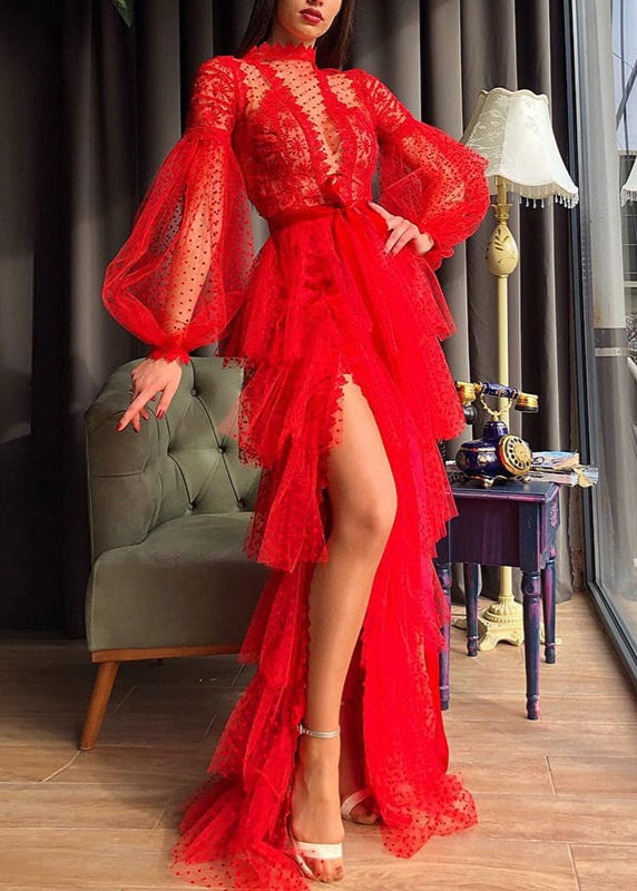 Frau in elegantem, rotem Spitzenkleid mit Rüschen und langen Ärmeln, steht neben grünem Sofa und Vintage-Telefon, modisch, glamourös.