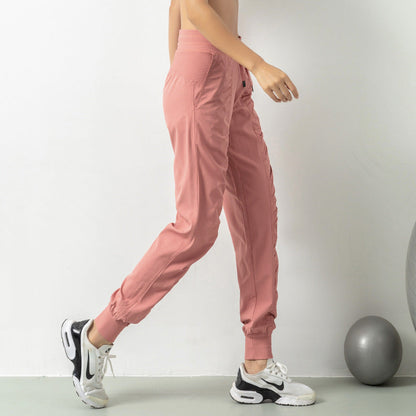 Person in rosa Jogginghose und weißen Sneakers beim Gehen, seitliche Ansicht. Sportbekleidung, Fitnessmode, bequeme Trainingshose.