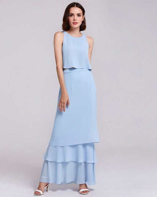 Frau in elegantem, hellblauem Abendkleid mit Stufenrock, ärmellosem Oberteil und weißen High Heels. Perfekt für formelle Anlässe und Sommermode.
