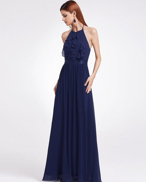 Frau in elegantem, langem, dunkelblauem Abendkleid mit Rüschen und Neckholder, ideal für formelle Anlässe. Elegante Mode, Abendgarderobe.
