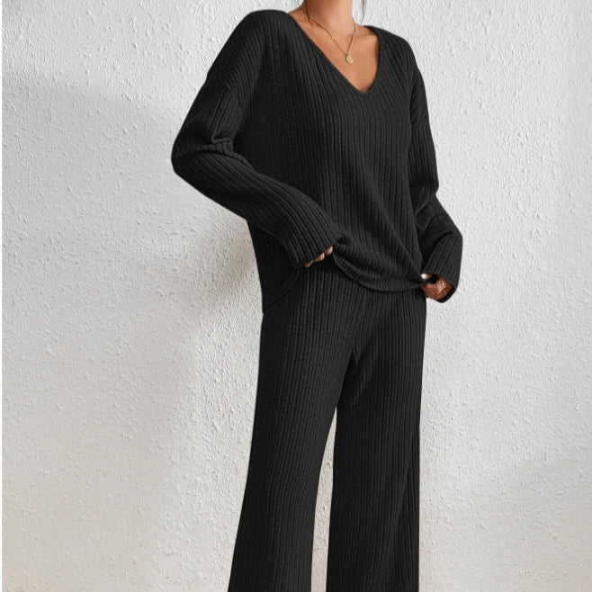 Frau in schwarzem, geripptem Strickpullover und Hose, V-Ausschnitt, lässiger Stil, minimalistische Mode, gemütliches Outfit, Herbst-Winter-Trend.