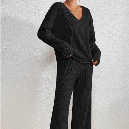 Frau in schwarzem, geripptem Strickpullover und Hose, V-Ausschnitt, lässiger Stil, minimalistische Mode, gemütliches Outfit, Herbst-Winter-Trend.