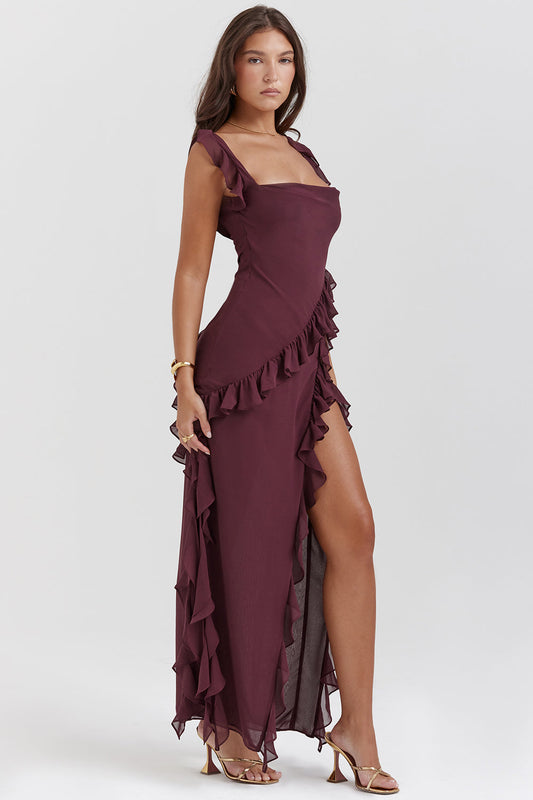 Frau in elegantem, weinrotem Abendkleid mit Rüschen und hohem Beinschlitz, goldene Sandalen, modisches Outfit, stilvolle Abendmode.