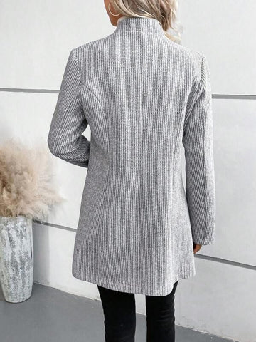 Frau in grauem, langem Blazer aus Strickstoff, Rückansicht. Modischer Damenmantel, elegantes Design, Herbstmode, urbaner Stil.