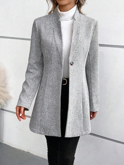 Frau in grauem, gestreiftem Blazer mit weißem Rollkragenpullover und schwarzer Hose. Elegante Damenmode, Herbstoutfit, stilvoller Look.