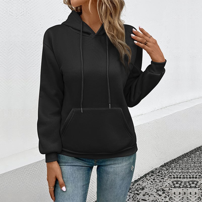 Frau in schwarzem Hoodie und blauer Jeans vor weißer Wand. Modetrend, lässiger Stil, Damenbekleidung, Herbstmode, Kapuzenpullover.
