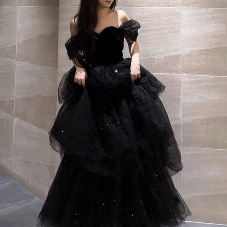 Frau in elegantem, schwarzem Abendkleid mit Tüll und Pailletten in modernem Innenraum. Luxuriöse Abendmode, glamouröses Design.