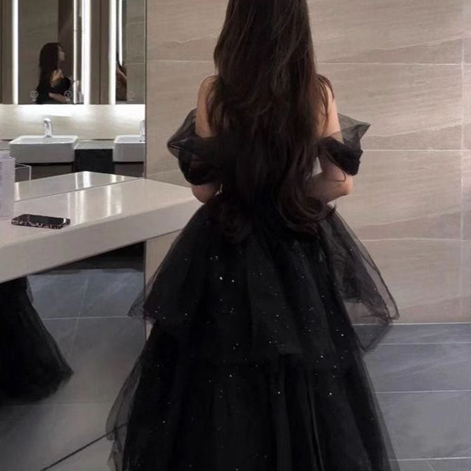 Frau in elegantem, schwarzem Abendkleid mit Tüll und Glitzer im modernen Badezimmer. Luxuriöse Mode, Abendgarderobe, stilvolles Design.