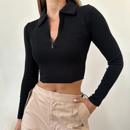 Frau trägt schwarzes Langarm-Crop-Top mit Reißverschluss und beige Hose. Modetrend, Damenbekleidung, stilvolles Outfit, Freizeitlook.
