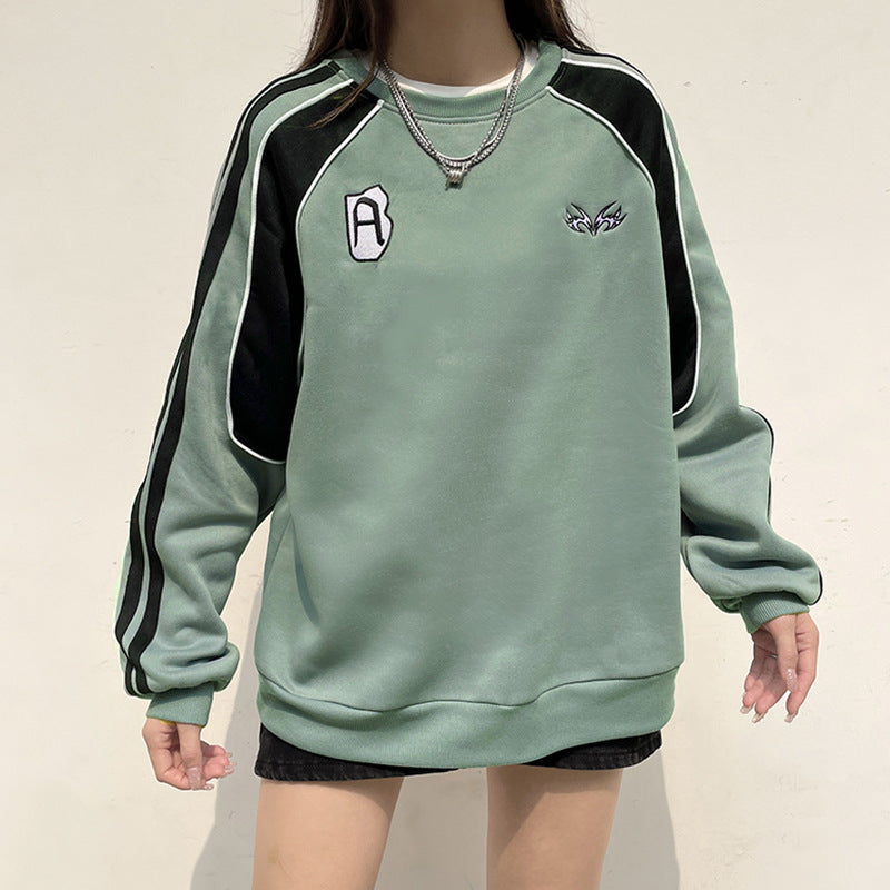 Grüner Oversize-Pullover mit schwarzen Streifen und weißen Applikationen, getragen von einer Person. Modetrend, lässiger Stil, Streetwear.