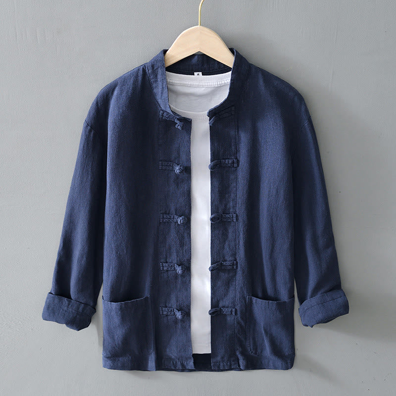 Dunkelblaue chinesische Jacke aus Leinen mit traditionellen Knöpfen, hängend auf einem Kleiderbügel vor grauem Hintergrund. Ideal für Herrenmode.