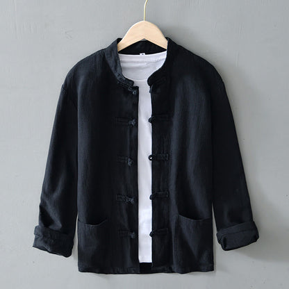Schwarze, traditionelle chinesische Jacke mit Stehkragen und Knotenverschlüssen, hängt auf einem Kleiderbügel vor grauem Hintergrund.