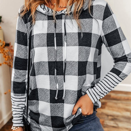 Frau trägt karierten Hoodie mit Kapuze, schwarz-weißes Muster, lässiger Stil, modisches Outfit, Herbstmode, gemütlicher Look, Innenaufnahme.