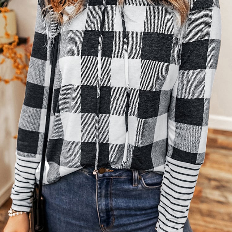Damenmode: Kariertes Langarmshirt in Schwarz-Weiß mit Kapuze, kombiniert mit blauer Jeans. Trendiges Outfit für Herbst und Winter.