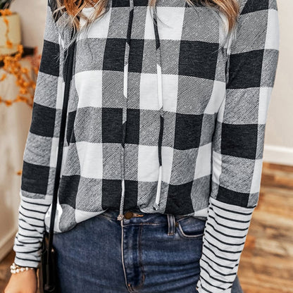 Damenmode: Kariertes Langarmshirt in Schwarz-Weiß mit Kapuze, kombiniert mit blauer Jeans. Trendiges Outfit für Herbst und Winter.