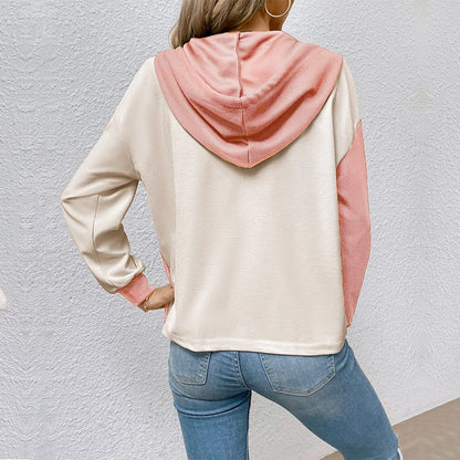 Frau in lässigem Hoodie mit rosa Kapuze und Ärmeln, kombiniert mit blauen Jeans. Modetrend, Freizeitkleidung, Damenmode.