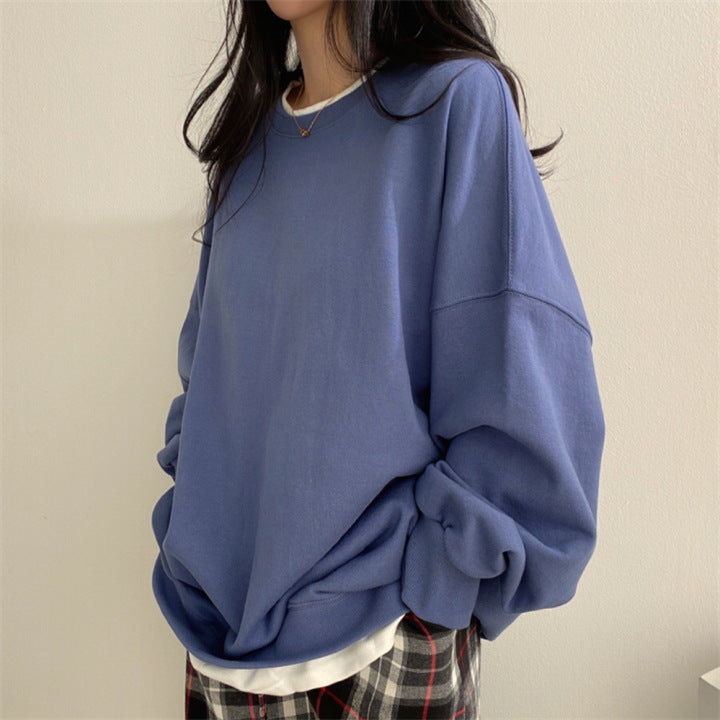 Frau in blauem Oversize-Pullover und karierter Hose, lässiger Stil, Mode für Herbst/Winter, gemütliches Outfit, trendige Damenbekleidung.