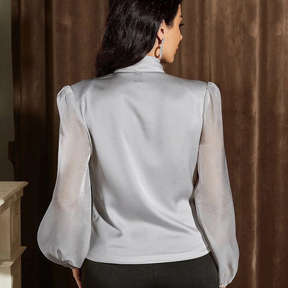 Frau in eleganter, weißer Satinbluse mit transparenten Ärmeln, Rückansicht. Modetrend, Damenbekleidung, stilvolle Bluse, schickes Outfit.