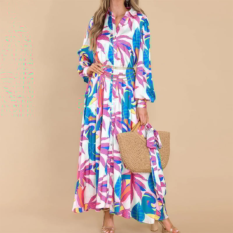Frau in langem, buntem Maxikleid mit tropischem Muster, hält eine Strohtasche. Perfekt für Sommermode, Strandkleidung, Freizeitoutfits.