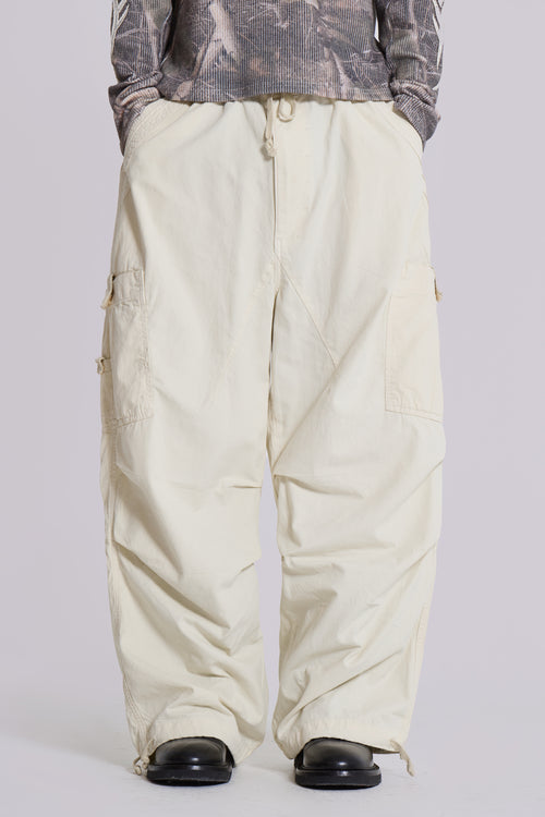 Beige Baggy-Cargohose, Unisex, mit mehreren Taschen, kombiniert mit schwarzem Schuhwerk. Modetrend, lässiger Streetwear-Stil, komfortabel und funktional.