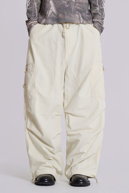 Beige Baggy-Cargohose, Unisex, mit mehreren Taschen, kombiniert mit schwarzem Schuhwerk. Modetrend, lässiger Streetwear-Stil, komfortabel und funktional.