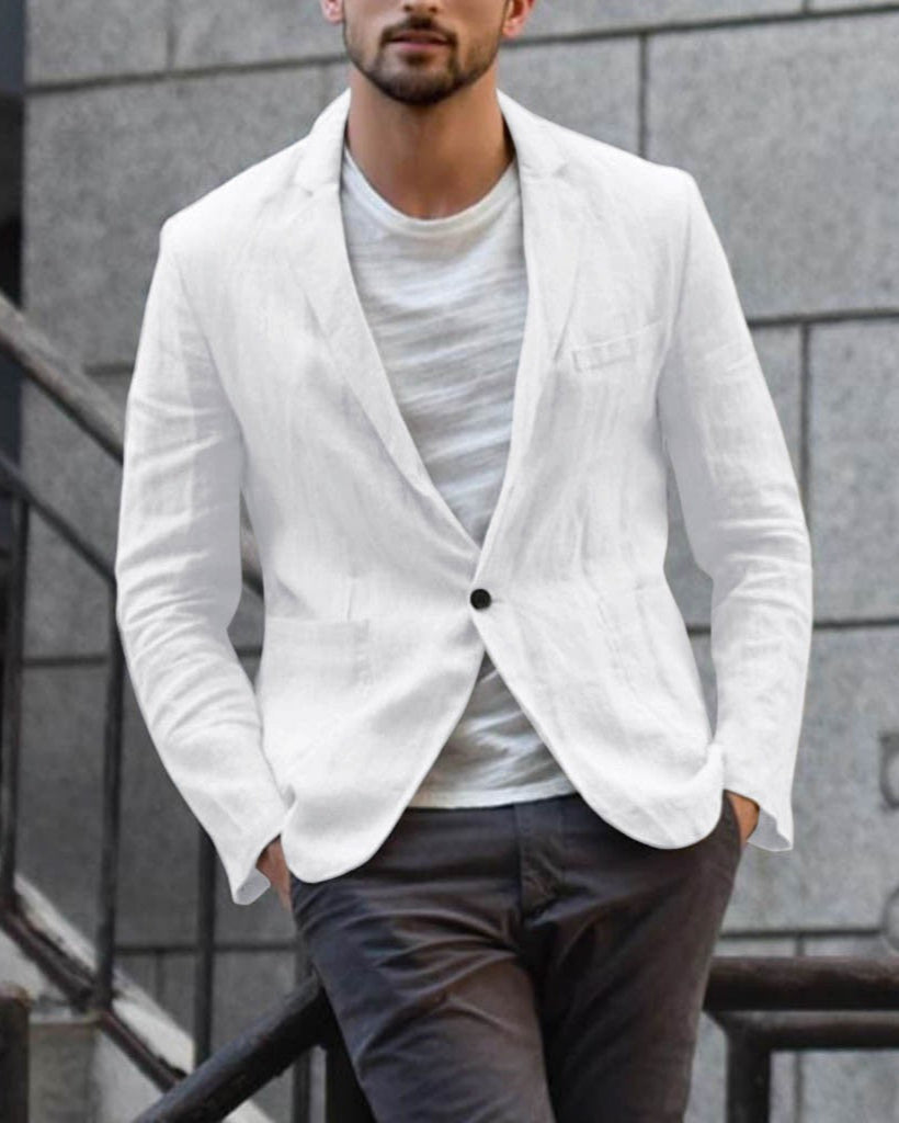 Mann in weißem Leinenblazer und grauer Hose vor urbanem Hintergrund. Elegante Herrenmode, stilvoller Freizeitlook, moderne Männermode.