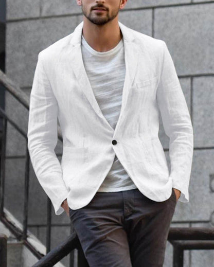 Mann in weißem Leinenblazer und grauer Hose vor urbanem Hintergrund. Elegante Herrenmode, stilvoller Freizeitlook, moderne Männermode.