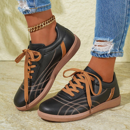 Schwarze Sneaker mit braunen Schnürsenkeln, getragen von Person in zerrissenen Jeans und goldener Fußkette. Modische Freizeitschuhe, Damenmode.