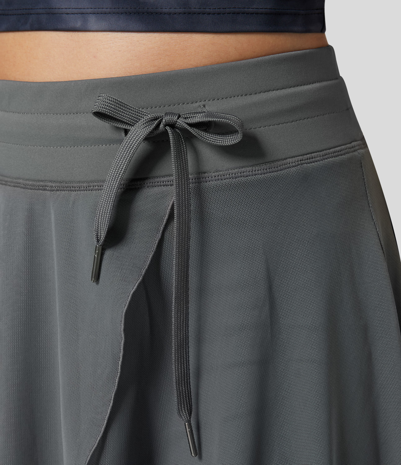Grauer Sportrock mit Kordelzug, Nahaufnahme. Bequemer, atmungsaktiver Stoff, ideal für Fitness und Freizeit. Moderner, funktionaler Stil.