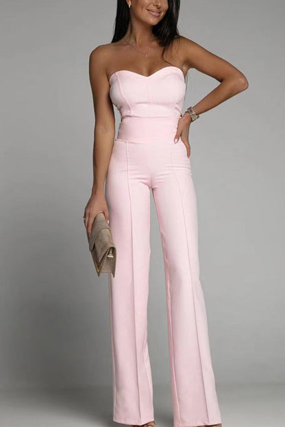 Frau in rosa schulterfreiem Jumpsuit, hält eine beige Clutch. Elegante Abendmode, modisches Outfit, stilvolle Damenbekleidung.