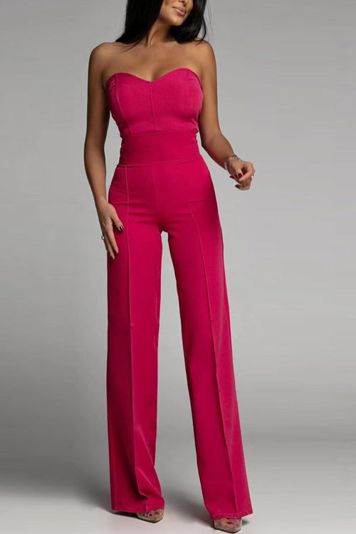 Frau in pinkem, schulterfreiem Jumpsuit, elegante Abendmode, modisches Outfit, trendige Damenbekleidung, stilvolle Kleidung für besondere Anlässe.