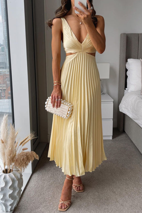 Frau in gelbem, plissiertem Abendkleid mit tiefem Ausschnitt, hält weiße Perlen-Clutch. Elegante Mode, Abendgarderobe, stilvolle Damenbekleidung.