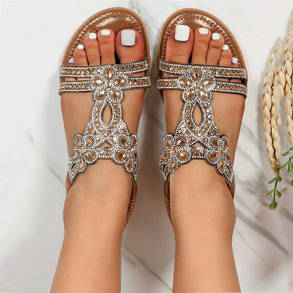 Damen Sandalen mit Strasssteinen, flach, elegant, Sommermode, weiße Pediküre, auf Marmorhintergrund, modische Fußbekleidung, trendige Accessoires.