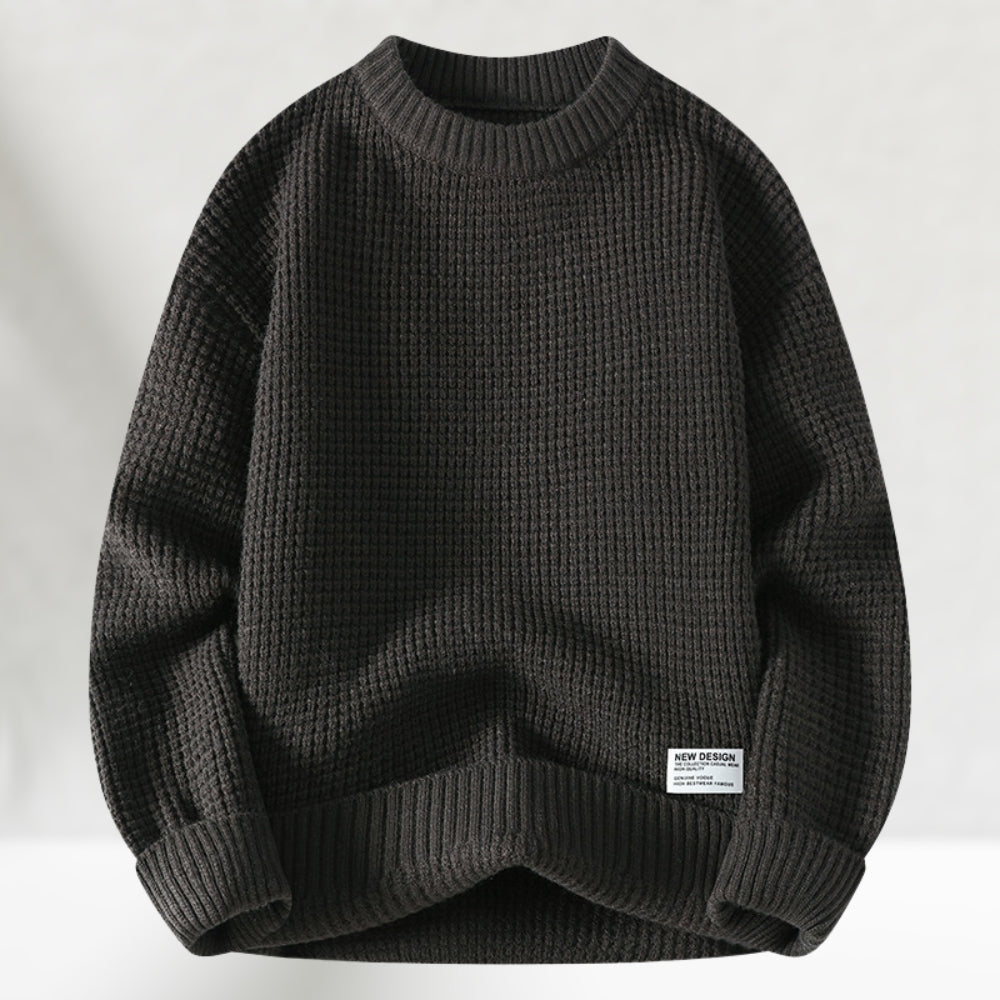Dunkelgrauer Strickpullover aus Baumwolle, grobmaschig, mit Rundhalsausschnitt und Etikett. Ideal für Herbstmode und lässige Outfits.