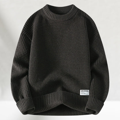 Dunkelgrauer Strickpullover aus Baumwolle, grobmaschig, mit Rundhalsausschnitt und Etikett. Ideal für Herbstmode und lässige Outfits.