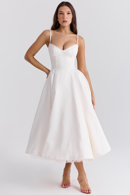 Frau in elegantem, weißem Abendkleid mit Spaghettiträgern und ausgestelltem Rock, stehend vor neutralem Hintergrund. Perfekt für Hochzeiten oder formelle Anlässe.