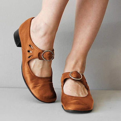 Braune Mary Jane Schuhe mit Riemen und Schnalle, niedriger Absatz, getragen von einer Person. Modische Damenschuhe, bequem und stilvoll.