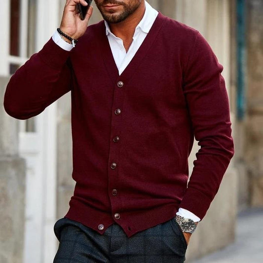 Mann in bordeauxroter Strickjacke, telefonierend, modisch gekleidet mit weißem Hemd und Armbanduhr, urbaner Hintergrund. Herrenmode, Herbstlook.