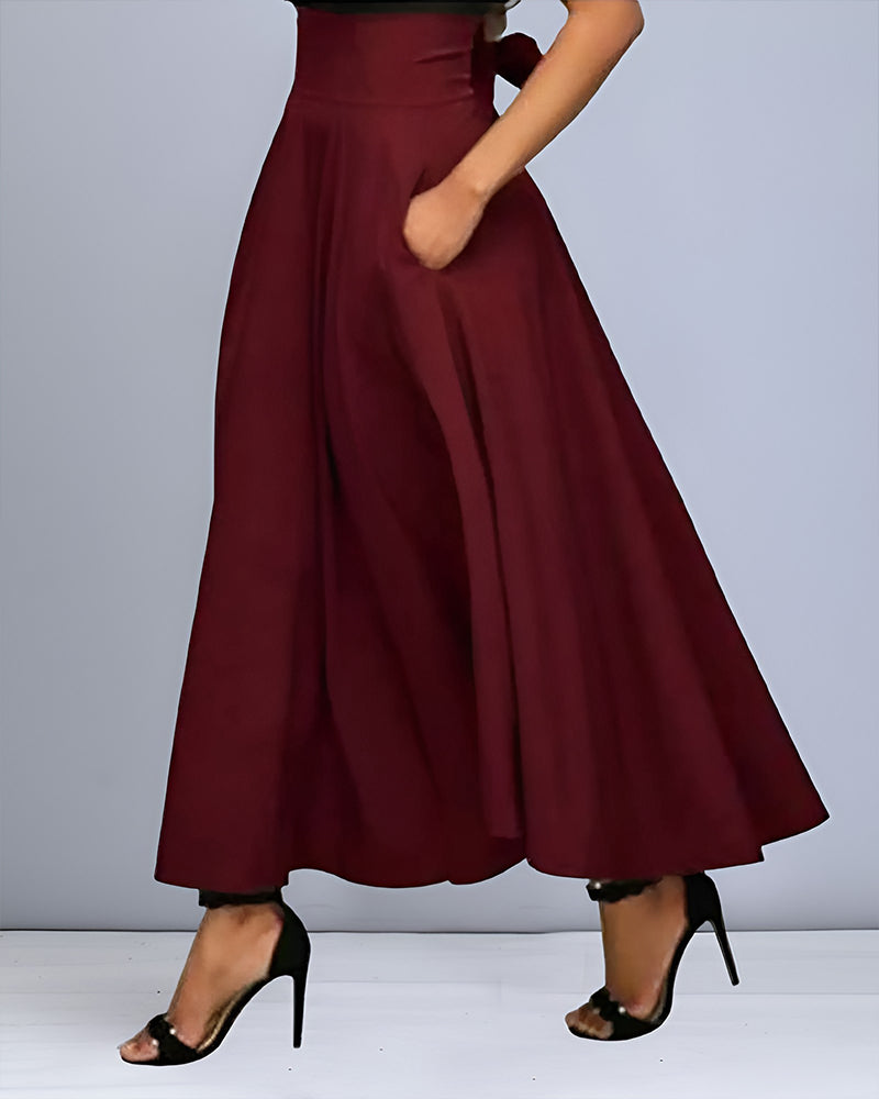 Frau in eleganter, weinroter, hoch taillierter Maxirock mit Taschen, kombiniert mit schwarzen High Heels. Modetrend, Damenmode, stilvoller Look.