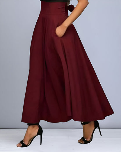 Frau in eleganter, weinroter, hoch taillierter Maxirock mit Taschen, kombiniert mit schwarzen High Heels. Modetrend, Damenmode, stilvoller Look.